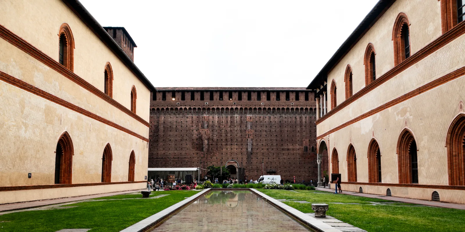 Castello Sforzesco avar sisehoov Milanos: punastest tellistest müürid hammasviiludega, muruplats ja pikk kitsas veesilm