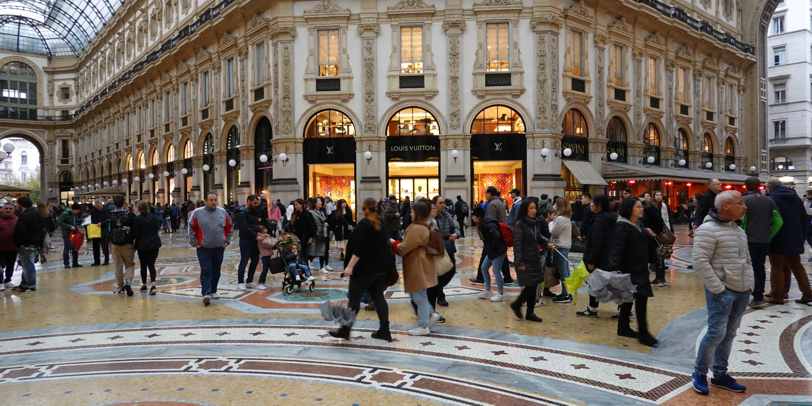 Galleria Vittorio Emanuele II kaarestikud ja marmorpõrand Milanos, inimesed jalutamas klaaskatuse all.