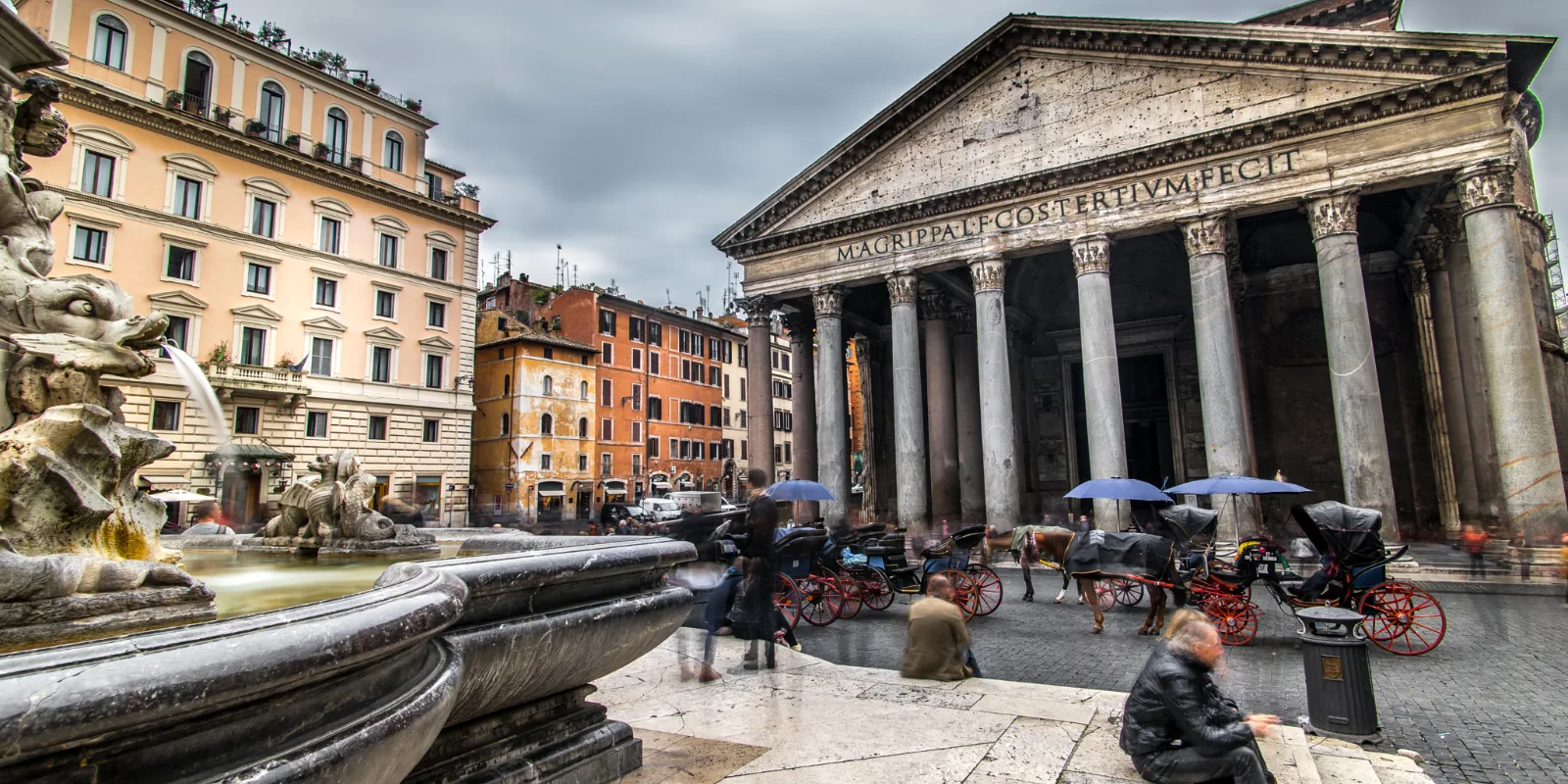 Panteoni sammastega esikülg Piazza della Rotonda väljakul Roomas, esiplaanil purskkaev ja hobuvankrid pilvisel päeval