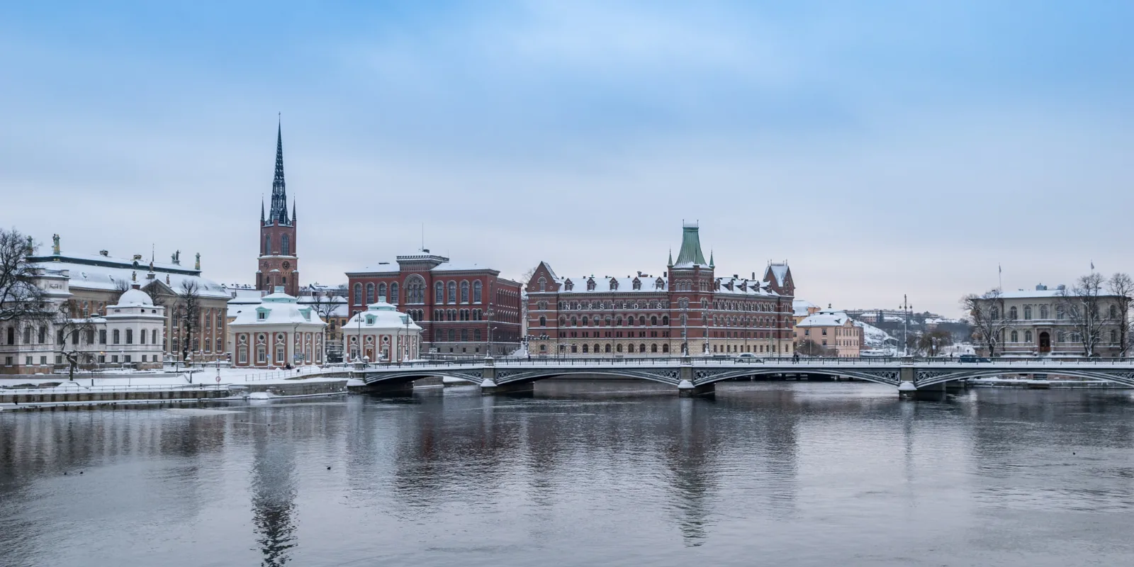 Talvine vaade üle vee Stockholmi vanalinna saarele, lumised katused ja kiriku torn