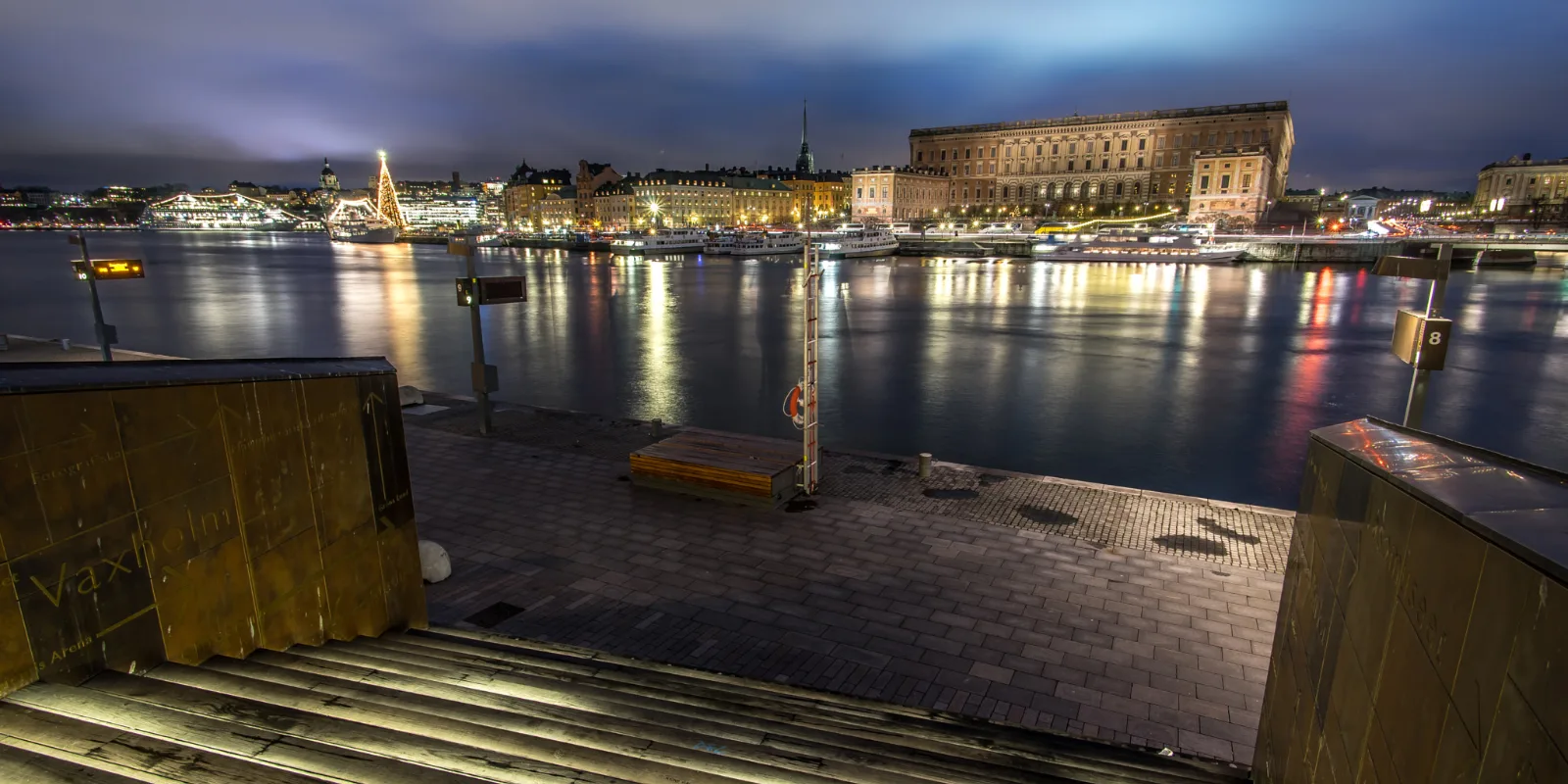 Stockholmi vanalinn ja kuningaloss öösel vee tagant vaadatuna, tuled peegeldumas vees